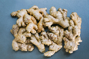 Heaping pile of whole ginger roots on silver surface / Holistic superfood healthy diet concept