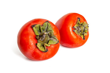 Two persimmon fruits, orange in color, with green leaves