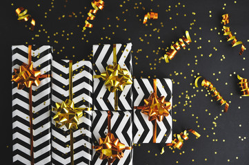 Christmas gifts with golden ribbons and bows on black background.