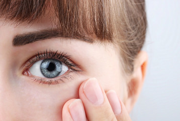 Obraz premium Piękne kobiece niebieskie oko i ręka na białym tle, koncepcja korekcji wzroku