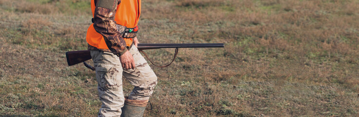 Hunter with a hat and a gun in search of prey in the steppe, Aims for prey. Panoramic image for...