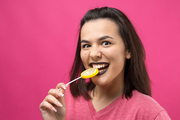 Portrait of lovely sweet beautiful cheerful woman with straight brown hair holding a lollipop near the eyes.