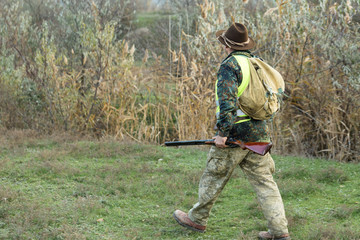 Hunting period, autumn season open. A hunter with a gun in his hands in hunting clothes in the...