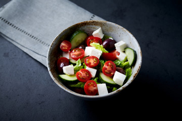Salad with Kalamata Olives, Cucumber Cherry Tomatoes and Feta Cheese on black Stone Background. Healthy Snack Idea. Copy space. 