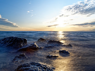 Obraz premium Hazy water over shoreline rocks near sunset. 