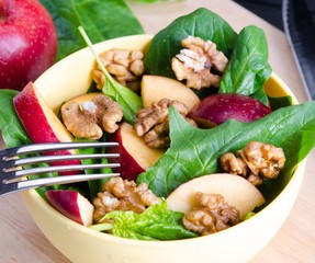 The spinach salad with nuts and apples served on table