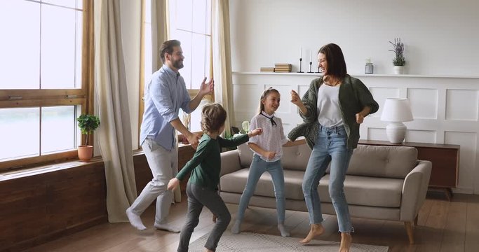 Crazy happy parents and children dancing jumping in living room