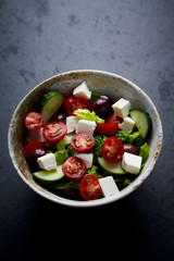 Salad with Kalamata Olives, Cucumber Cherry Tomatoes and Feta Cheese on black Stone Background. Healthy Snack Idea. Copy space. 