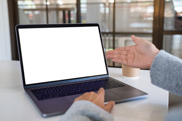 Mockup image of a woman pointing hand and touching on laptop touchpad with blank white desktop screen in office