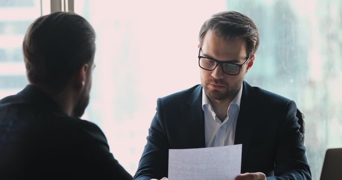Serious businessman employer holding cv interviewing male job applicant
