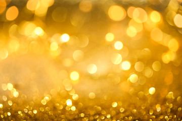 Abstract bokeh of glowing yellow lights and sparkling gold glitter background or wallpaper