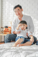 Fototapeta premium Asian Japanese Family father mother son wearing white shirt carrying child posing for photo on bedroom in white room.To keep memories moment cuteness of son in childhood