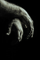 verry old male praying hands with ring in front of black background