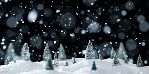 Wintry forest scene of miniature snow covered trees on glittering snow drifts surrounded by falling snow