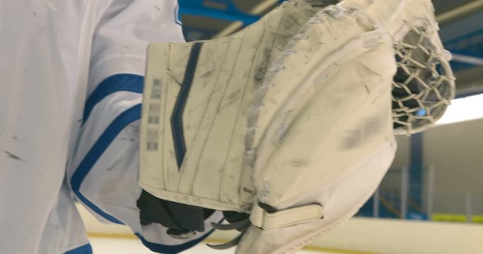 Hockey goalkeeper catches the puck with his white glove trapper