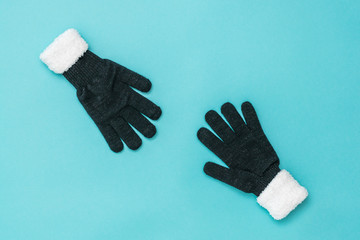 Two women's gloves stretch towards each other on a blue background. The concept of hope and meeting.