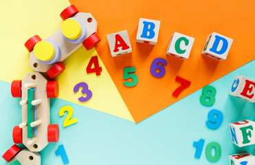 Wooden kids toys on colourful paper. Educational toys blocks, pyramid, pencils, numbers, train. Toys for  kindergarten, preschool or daycare. Copy space for text. Top view