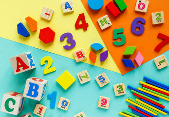 Wooden kids toys on colourful paper. Educational toys blocks, pyramid, pencils, numbers, train. Toys for kindergarten, preschool or daycare. Copy space for text. Top view