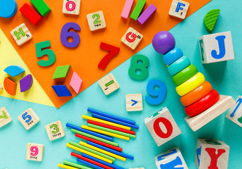 Wooden kids toys on colourful paper. Educational toys blocks, pyramid, pencils, numbers, train. Toys for  kindergarten, preschool or daycare. Copy space for text. Top view