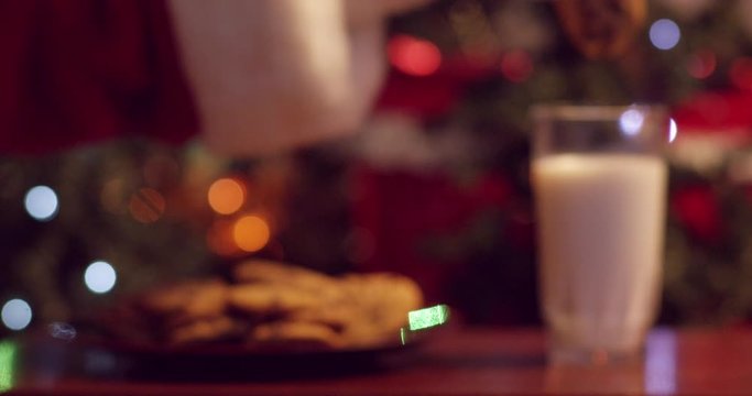 Santa dunking cookies in milk in front of the Christmas tree - soft focus - shot on RED