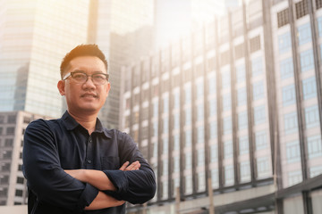 Fototapeta premium Confident male business executive with arms crossed standing in front of office building