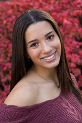 Portrait of mixed raced teenage girl smiling with red fall leaves in the background