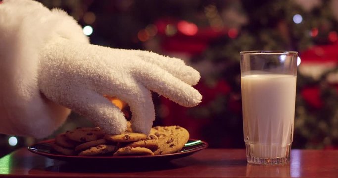 Santa dunking cookies in milk in front of the Christmas tree - slow motion - shot on RED