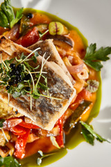 Pollock fish fillet with vegetables on white plate
