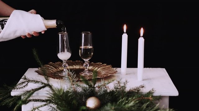 Female hand pours champagne into a glass on Christmas Table Setting