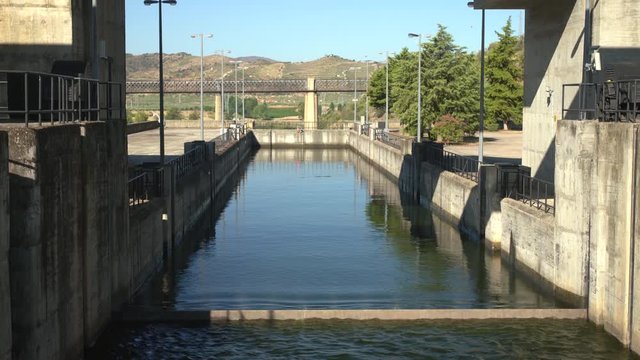 Closer view of Barragem do Pocinho dam as a river cruise boat on the Douro waits as the lock gate drops under the water surface