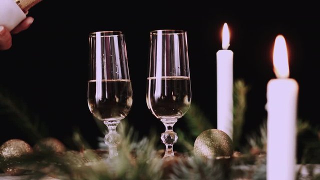 Two glasses with champagne with christmas decor, sparkler background and candles