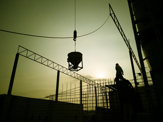 workman is Work at height, stone and water to make cement wall, construction site before the concrete was poured, pouring concrete by bracket on mobile crane, photo is yellow filter