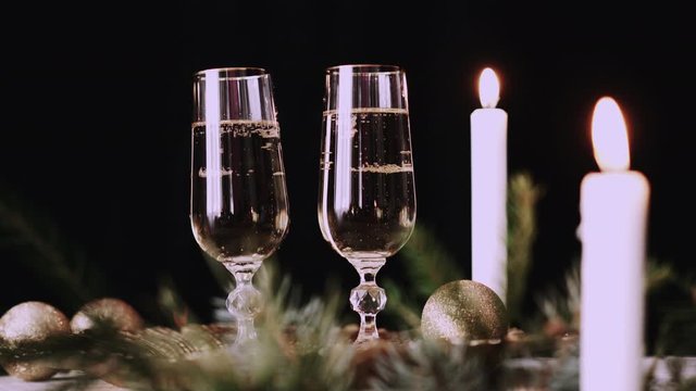 Two glasses with champagne with christmas decor, sparkler background and candles