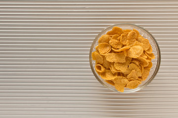 Cornflakes in a plate on a silver background. The view from the top.