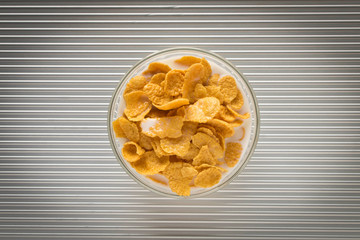Cornflakes with milk in a plate on a silver background. The view from the top.