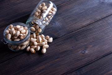 Pistachios in glass jars on a wooden background