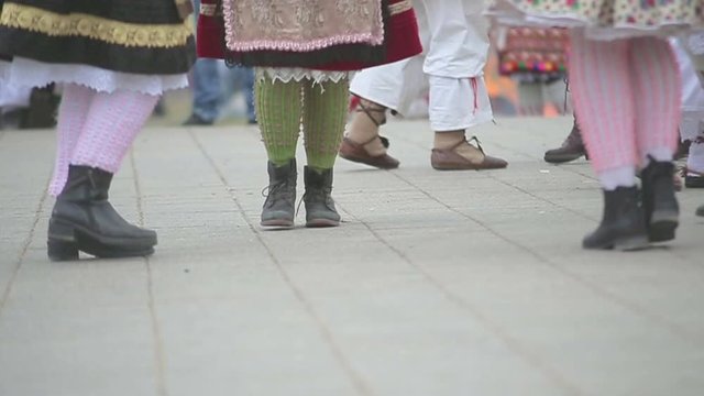 Closeup of women group and their legs and shoes while  rhythmically dancing in traditional bizarre buso outfit at Mohacs Hungary festival in cold winter. Slow motion footage in movement.