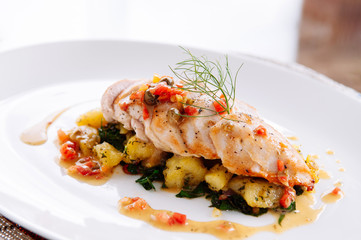 Grill chicken breast with baked potato and kale lemon butter sauce serving in white plate