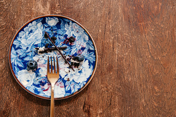 Blueberry cake already eaten left some stain on beautiful luxury ceramic dish with brass fork