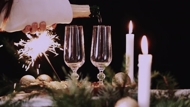 Female hand pours champagne into a glass on Christmas Table Setting