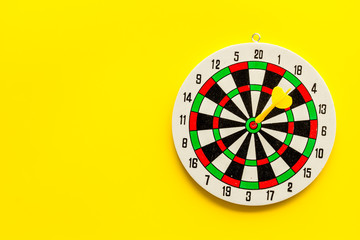 Obraz premium Accuracy of precision concept. Dartboard and arrows on yellow background top view copy space