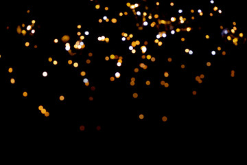 Fototapeta na wymiar Golden glitter bokeh lights on black background, unfocused. Holiday time.