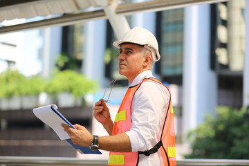 The engineer holding tablet standing against  building. The concept of engineering, construction, city life and future.