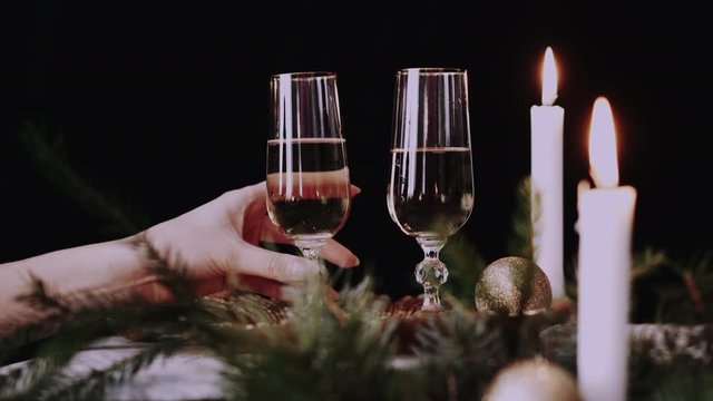 Female hand takes a glass with champagne christmas decor background and candles