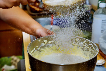 Woman sifts the flour in mixer bowl with dough. Making cake dough.