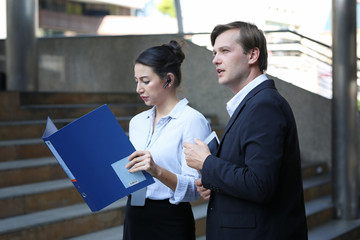 Concept of partnership in business. Young man and woman talking on business while walking on footbridge.