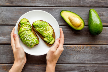 Healthy breakfast. Avocado toast on dark wooden background top view copy space