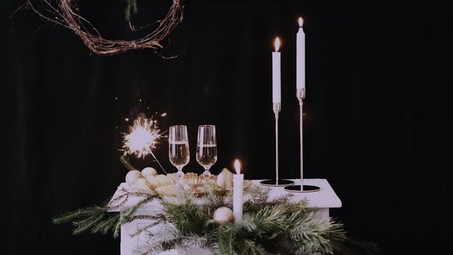 Two glasses with champagne with christmas decor, sparkler background and candles