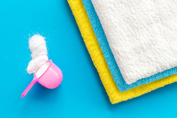 Laundry concept. Clean linen near washing powder on blue background top view