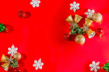 Christmas background concept. Top view of Christmas golden bells with balls decoration, spruce branches, star and snowflakes on red background.